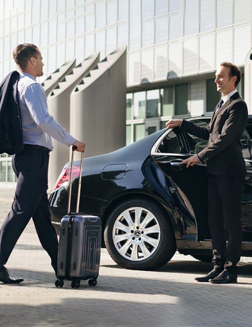 Philly Airport Shuttles | Airport Taxi Services ,a person coming from the airport with his bag and a person welcomes him with luxury sedan